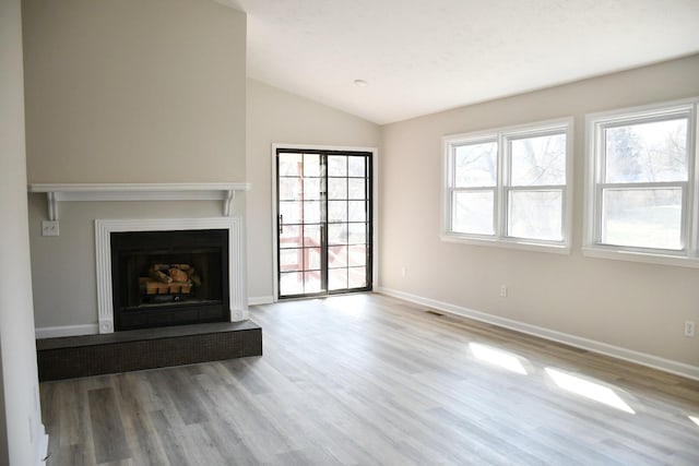 unfurnished living room featuring lofted ceiling and light wood-type flooring