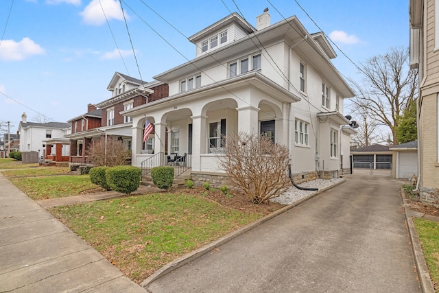 american foursquare style home featuring a chimney, a porch, a detached garage, and brick siding