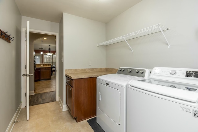 laundry room featuring cabinet space, baseboards, and separate washer and dryer