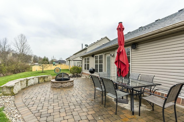 view of patio with an outdoor fire pit, outdoor dining area, and fence