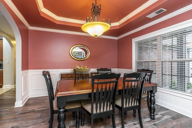 dining space with dark wood-style floors, visible vents, arched walkways, and a tray ceiling