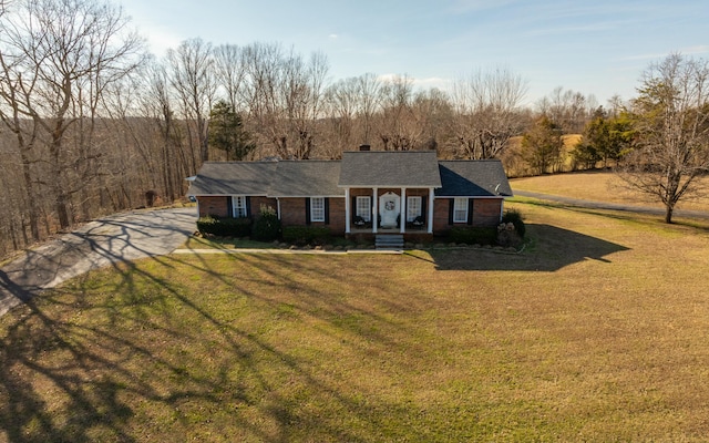 view of front of house featuring a front yard, brick siding, and a chimney