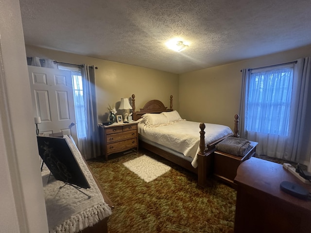 bedroom featuring dark colored carpet and a textured ceiling