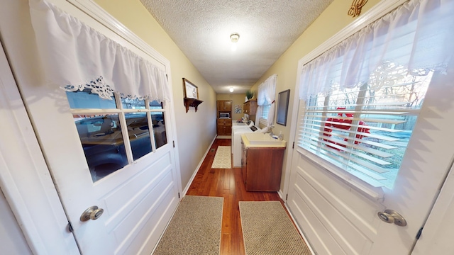 corridor with dark wood-type flooring, sink, and a textured ceiling