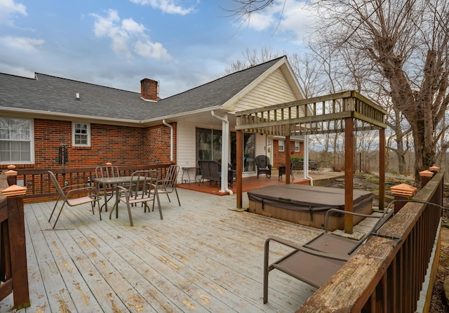 deck with outdoor dining area, a covered hot tub, and a pergola