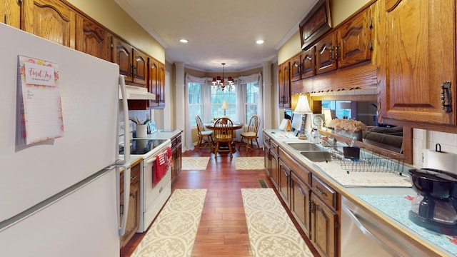 kitchen with pendant lighting, white appliances, dark hardwood / wood-style floors, ornamental molding, and decorative backsplash