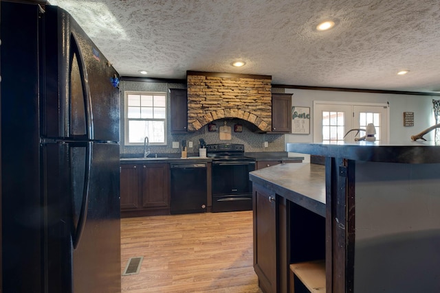 kitchen with sink, light hardwood / wood-style flooring, black appliances, and a textured ceiling