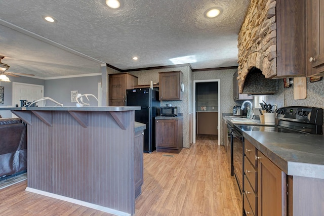 kitchen with sink, light hardwood / wood-style flooring, black appliances, and a kitchen island