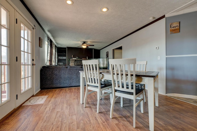 dining space featuring ceiling fan, wood-type flooring, ornamental molding, and a textured ceiling