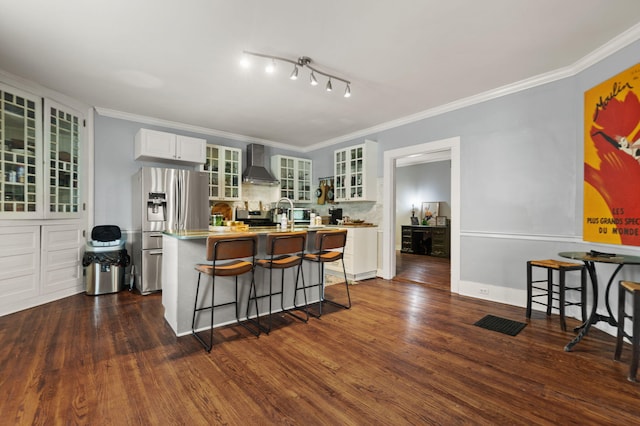 kitchen with a breakfast bar, dark hardwood / wood-style floors, stainless steel fridge, an island with sink, and wall chimney range hood