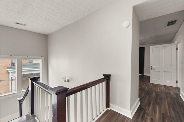 hallway with dark wood-type flooring and a textured ceiling