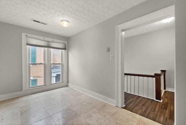 tiled empty room with a textured ceiling