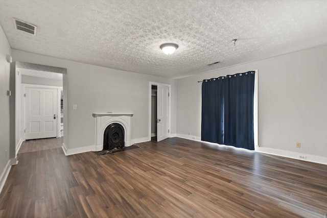 unfurnished living room with a textured ceiling and dark hardwood / wood-style flooring