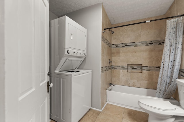 bathroom with tile patterned floors, toilet, a textured ceiling, shower / bath combination with curtain, and stacked washing maching and dryer