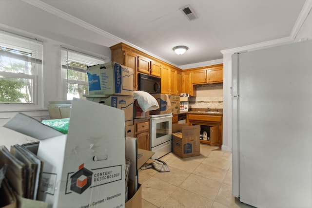 kitchen with tasteful backsplash, crown molding, fridge, and oven