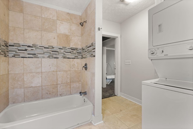 bathroom with stacked washer and dryer, tiled shower / bath, tile patterned floors, and a textured ceiling