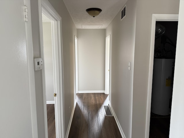 hallway featuring dark hardwood / wood-style floors, electric water heater, and a textured ceiling