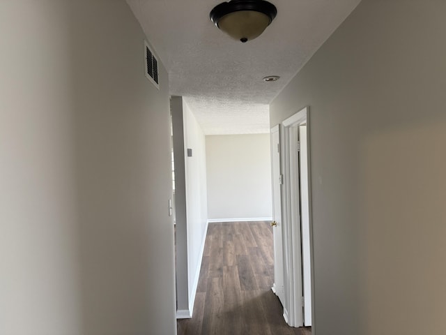 hall with dark wood-type flooring and a textured ceiling