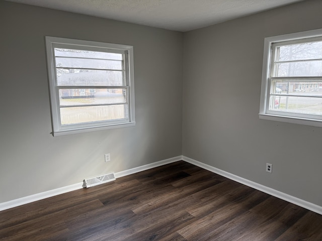 unfurnished room featuring dark wood-type flooring and a textured ceiling