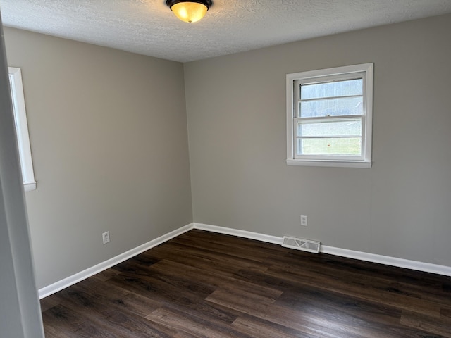 unfurnished room featuring a textured ceiling and dark hardwood / wood-style flooring