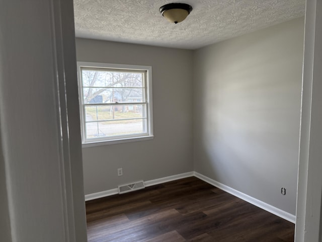 unfurnished room with dark hardwood / wood-style flooring and a textured ceiling