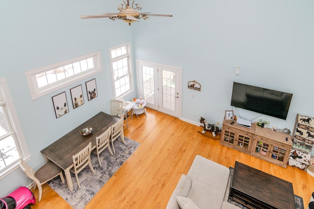 living area featuring a ceiling fan, a towering ceiling, and wood finished floors