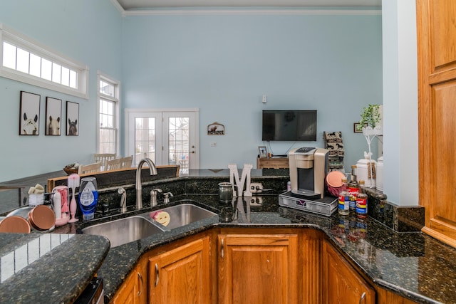 kitchen featuring dark stone countertops, brown cabinets, and a sink