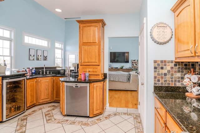 kitchen featuring light tile patterned floors, a sink, dark stone counters, beverage cooler, and dishwasher