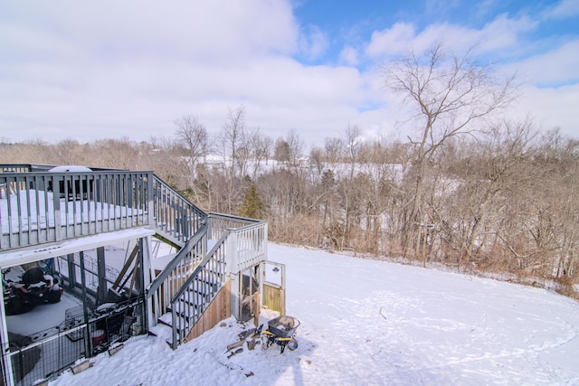 snowy yard featuring stairway and a wooden deck