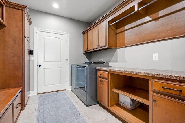 clothes washing area featuring cabinets, washer and dryer, and light tile patterned floors