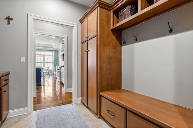 mudroom featuring light tile patterned floors and a tray ceiling