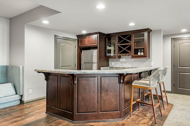 bar featuring dark brown cabinets, sink, stainless steel fridge, and dark hardwood / wood-style floors