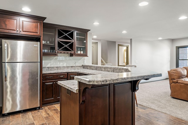 kitchen featuring stainless steel refrigerator, dark brown cabinets, a breakfast bar area, and light hardwood / wood-style flooring