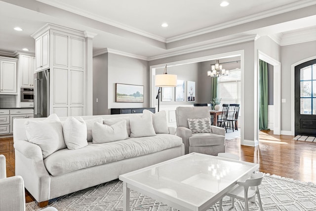 living room with a notable chandelier, ornamental molding, and light hardwood / wood-style floors