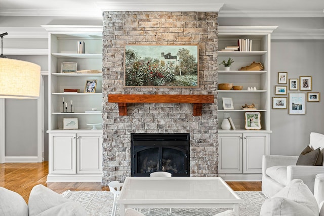 living room with crown molding, a large fireplace, and light hardwood / wood-style flooring