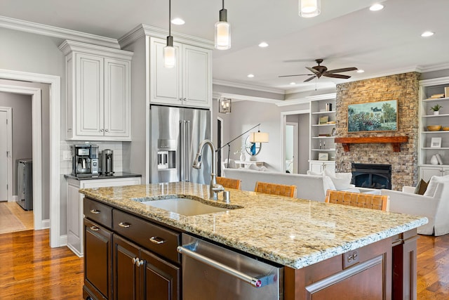 kitchen featuring a kitchen bar, sink, white cabinetry, appliances with stainless steel finishes, and ornamental molding