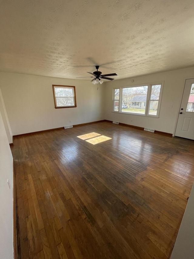 interior space featuring plenty of natural light, dark wood-type flooring, and a textured ceiling