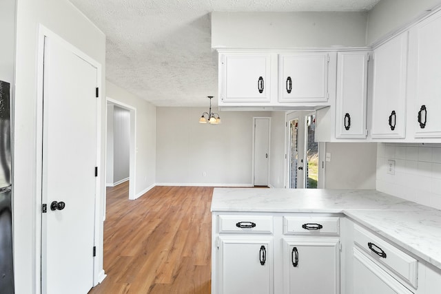 kitchen featuring decorative light fixtures, tasteful backsplash, white cabinets, a textured ceiling, and light hardwood / wood-style flooring