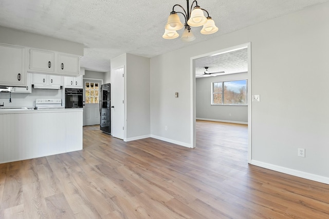 kitchen with decorative light fixtures, white cabinets, light wood-type flooring, and black appliances