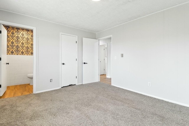 unfurnished bedroom with light colored carpet, a textured ceiling, and ensuite bathroom