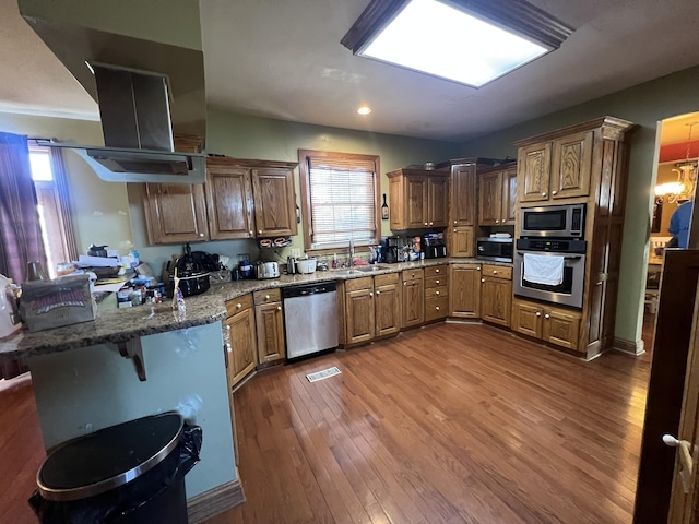 kitchen featuring dark wood-type flooring, sink, appliances with stainless steel finishes, kitchen peninsula, and light stone countertops