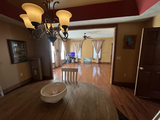 dining area with wood-type flooring and ceiling fan with notable chandelier