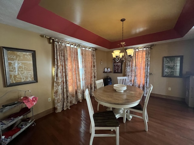 dining room with an inviting chandelier, a tray ceiling, and dark hardwood / wood-style floors