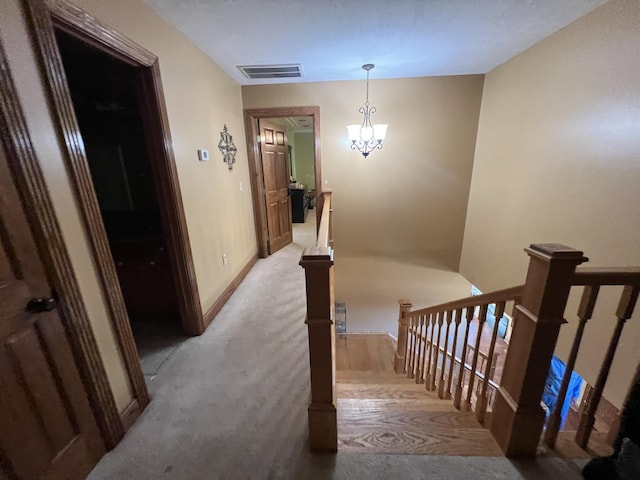 stairway with carpet floors and a notable chandelier