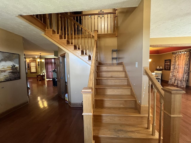 stairway with hardwood / wood-style floors, a textured ceiling, and a high ceiling