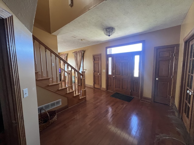 entrance foyer with dark wood-type flooring and a textured ceiling