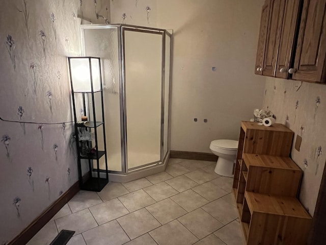 bathroom featuring tile patterned floors, toilet, and a shower with shower door