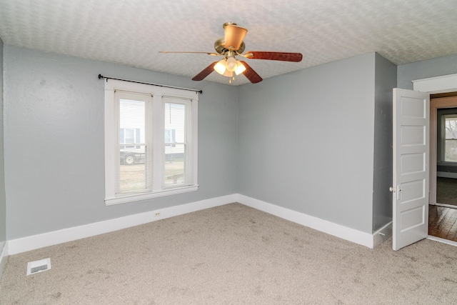 carpeted spare room with ceiling fan and a textured ceiling