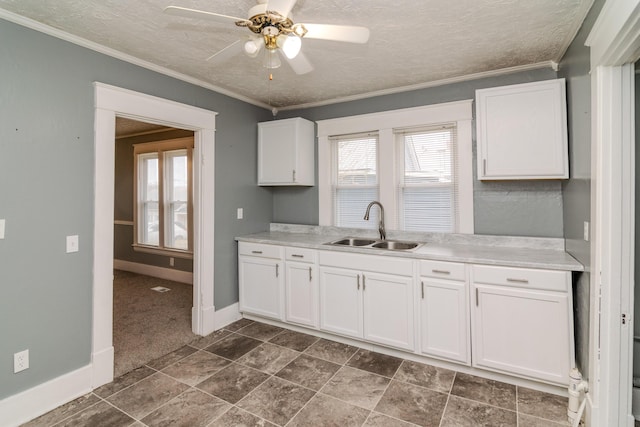 kitchen with crown molding, sink, white cabinets, and a textured ceiling