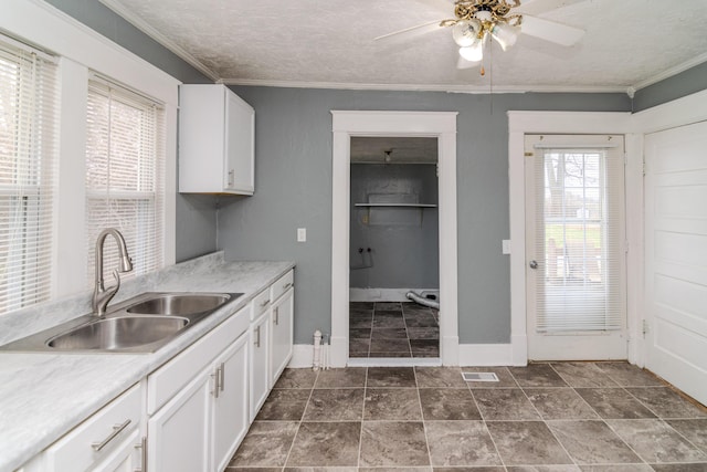 kitchen with white cabinetry, sink, ceiling fan, crown molding, and a textured ceiling